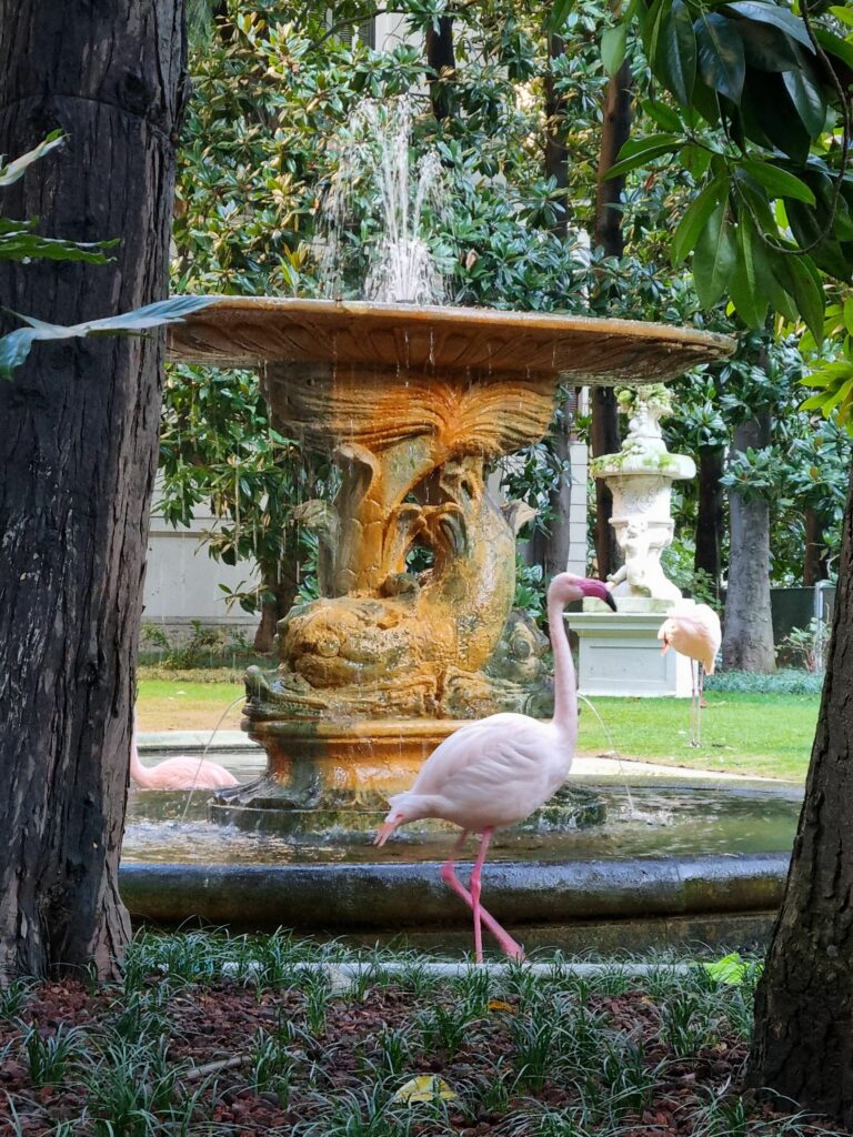 Fontanna z rzeźbami i flamingami w zielonym ogrodzie w Mediolanie