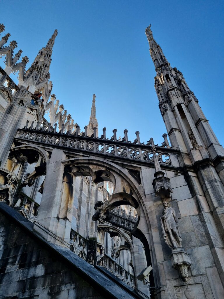 Gotyckie łuki, rzeźby i pinakle na dachu Katedry Duomo w Mediolanie