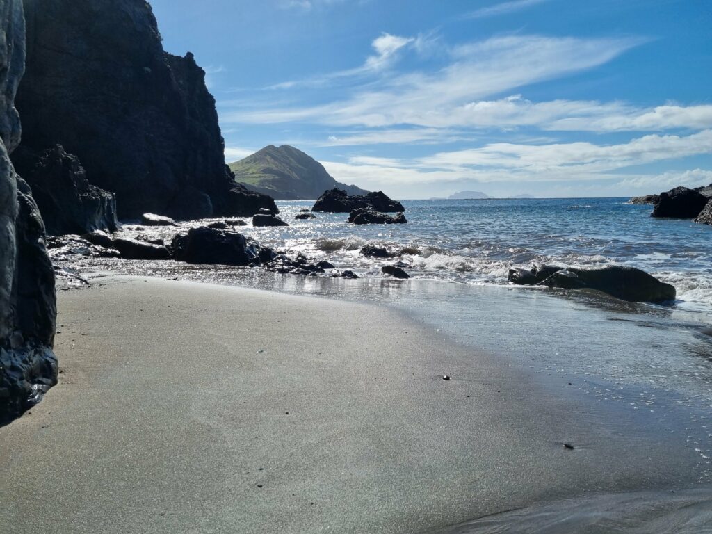 Plaża Baía D'Abra z czarnym piaskiem u podnóża skalistego klifu na Ponta de São Lourenço