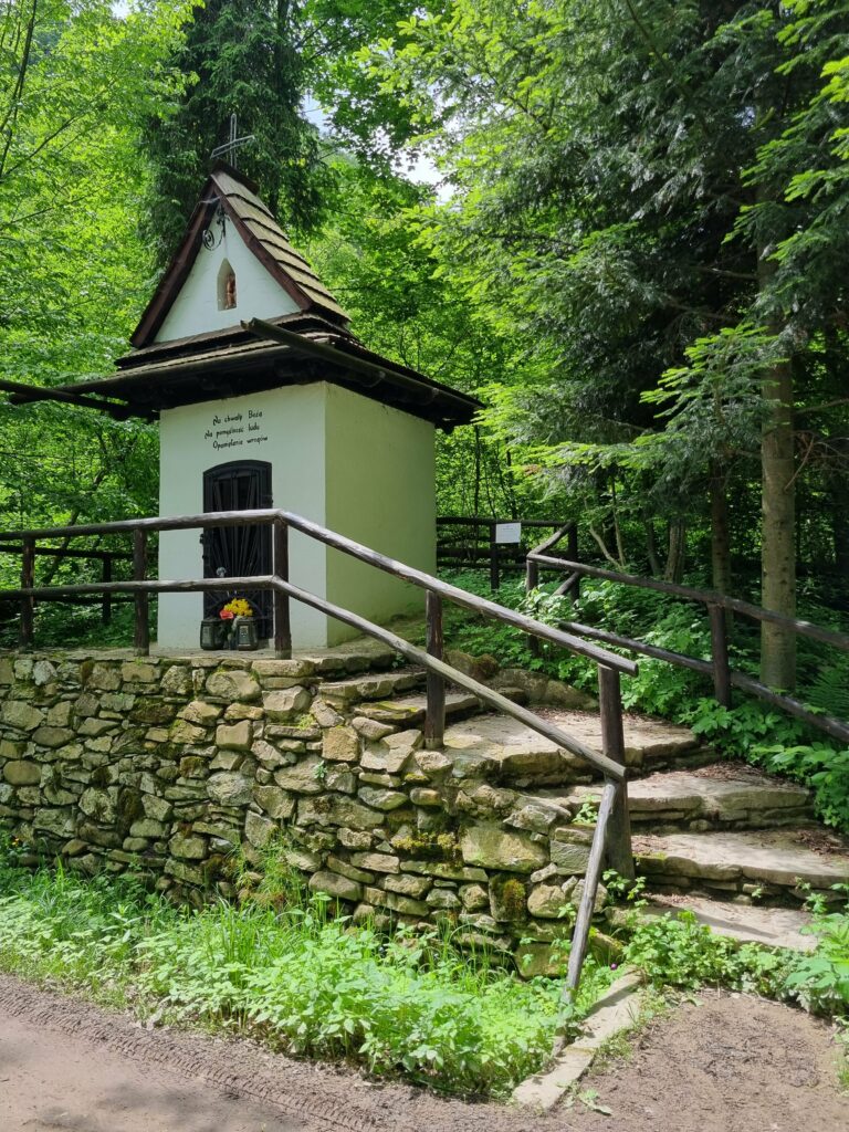 Kapliczka przy leśnej ścieżce otoczona drzewami w Krościenku nad Dunajcem
