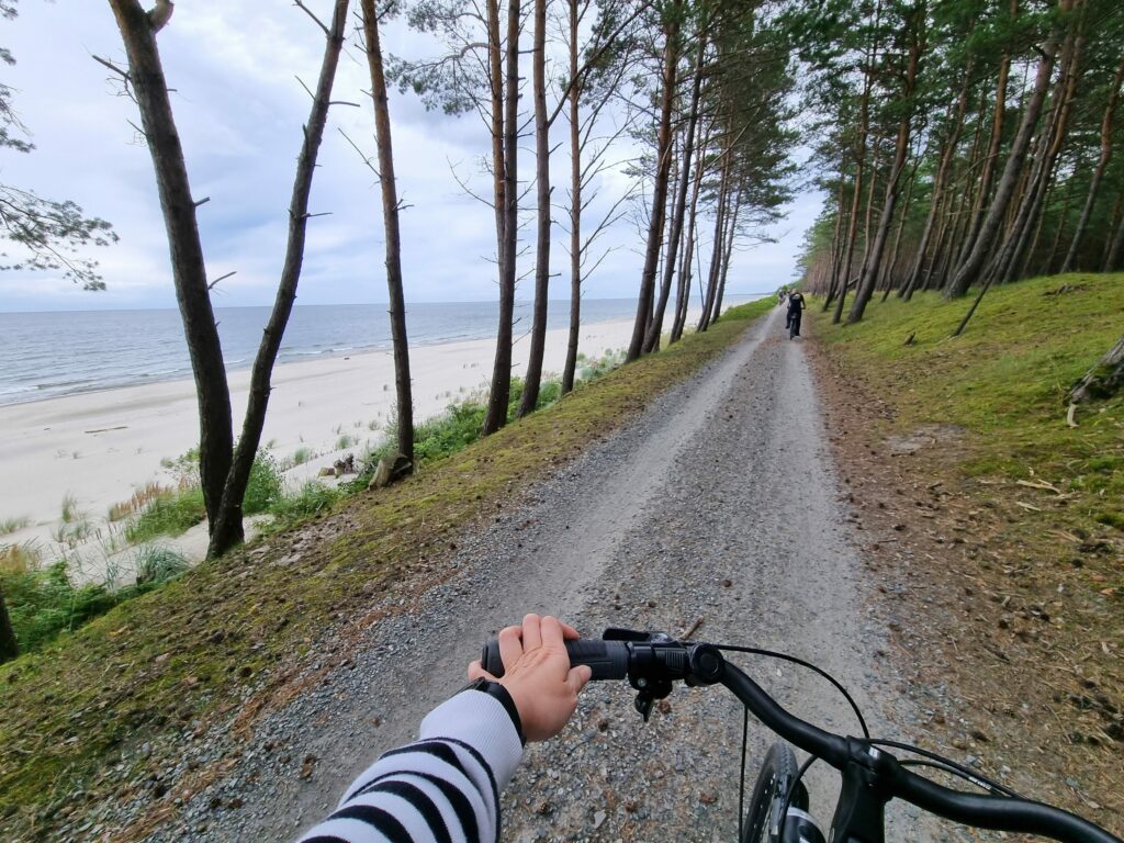 Jazda rowerem po szutrowej drodze na Mierzei Wiślanej, obok plaży i morza.