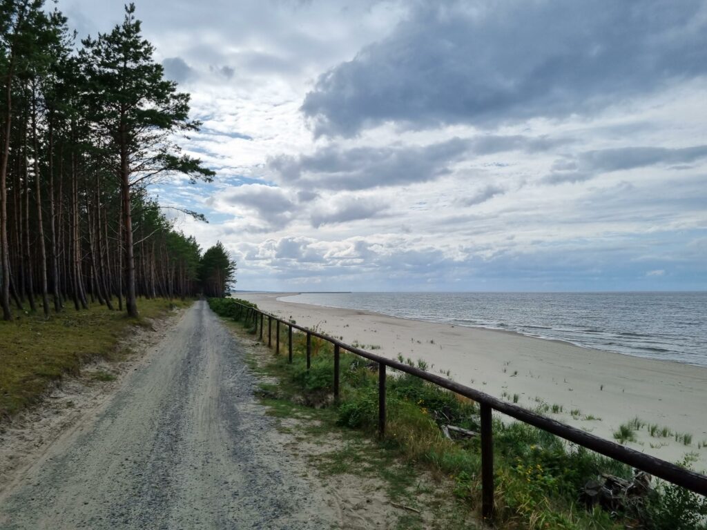 Szlak rowerowy na Mierzei Wiślanej, obok piaszczystej plaży i morza.