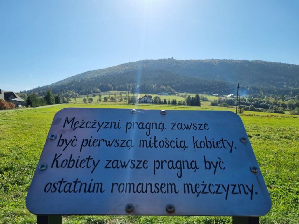 Tablica z sentencją o miłości w otoczeniu Beskidu Wyspowego.