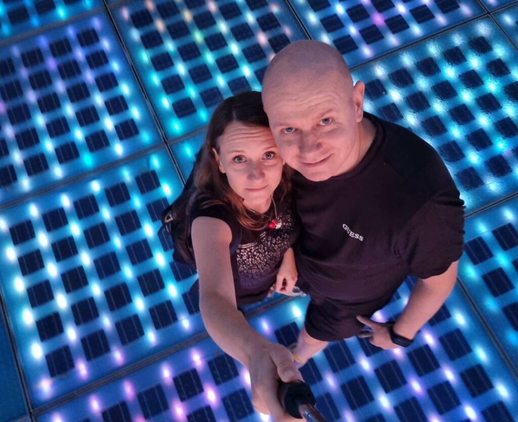 Para robiąca selfie na świecącej, kolorowej instalacji Pozdrowienie Słońca w Zadarze w nocy, Chorwacja.