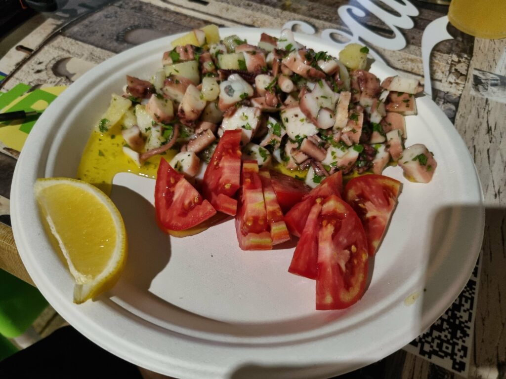 Chorwacka sałatka z ośmiornicy (salata od hobotnice) z ziemniakami, pomidorami i pietruszką, podana na talerzu.