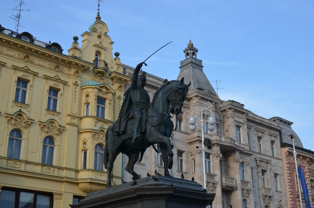 Pomnik konny bana Josipa Jelačicia na głównym placu Zagrzebia. W tle widoczne są zabytkowe, eleganckie kamienice centrum miasta.