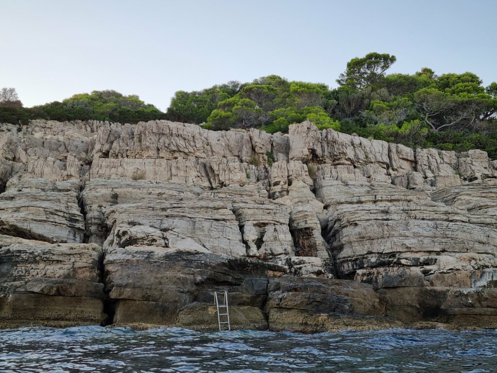Skalisty, wapienny klif z metalową drabinką prowadzącą do morza na wybrzeżu w pobliżu Dubrownika, wyspa Lokrum.