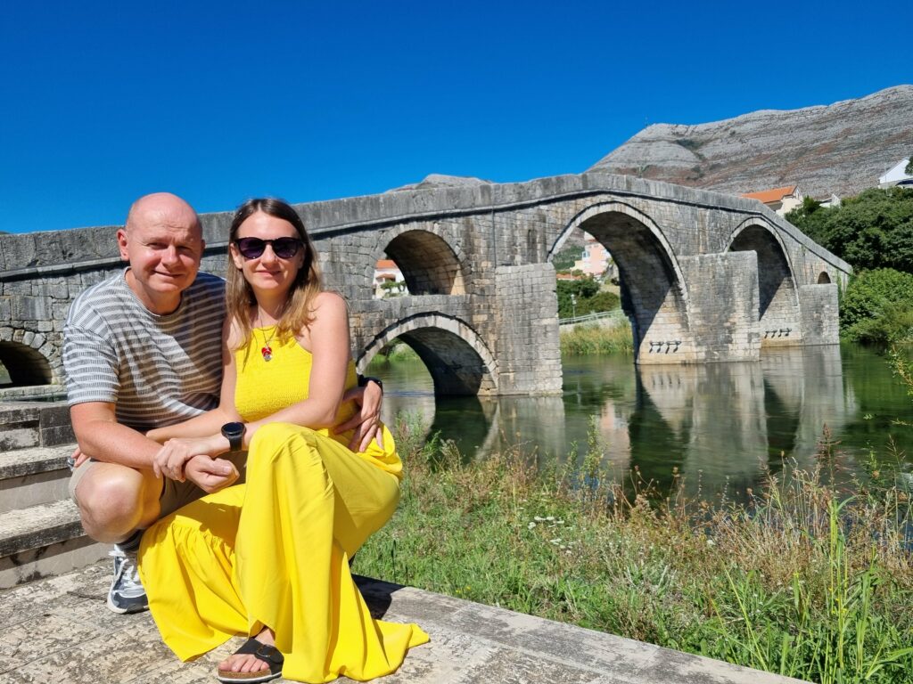 Para turystów na tle kamiennego Mostu Arslanagića w Trebinje, Bośnia i Hercegowina, nad rzeką Trebišnjica.