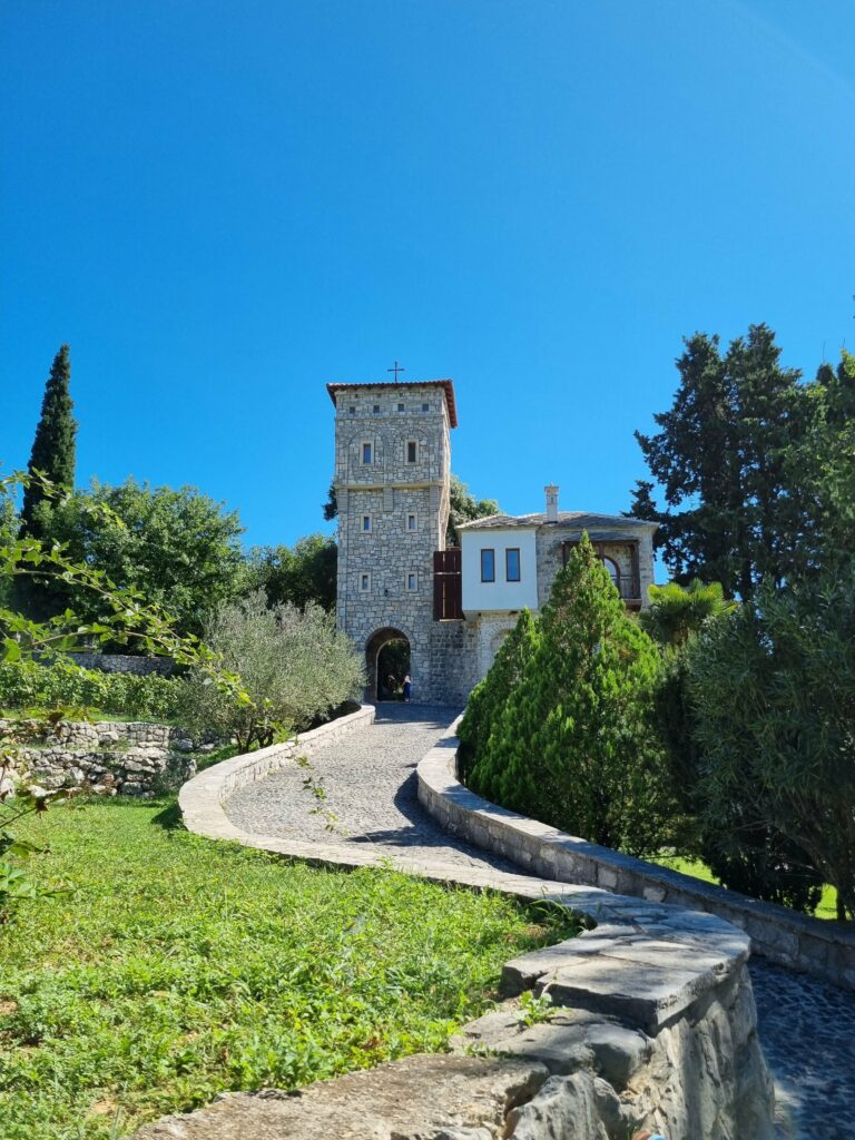 Kamienna wieża klasztorna i budynki Monasteru Tvrdoš na tle błękitnego nieba i zieleni w Bośni i Hercegowinie.