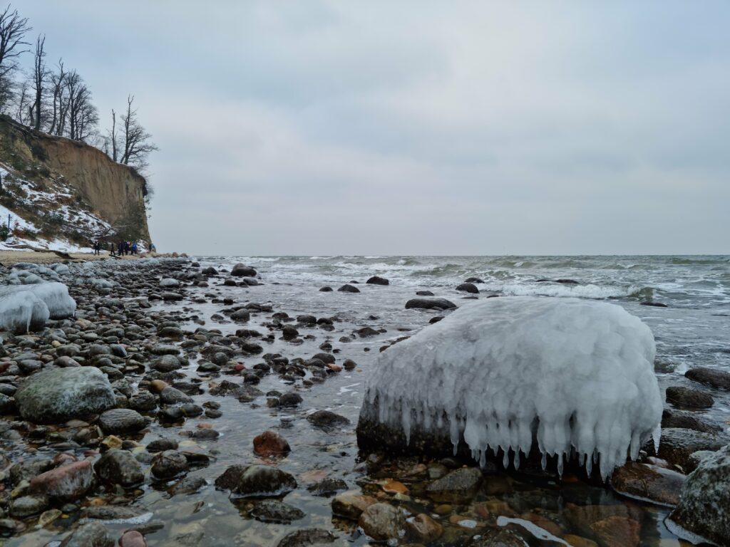Duży kamień pokryty czapą lodową na brzegu morza pod Klifem Orłowskim