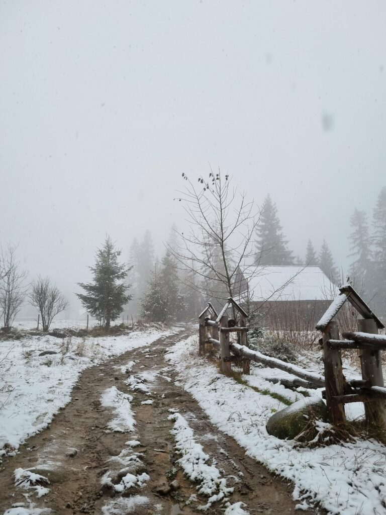 Błotnista i ośnieżona droga gruntowa z drewnianym płotem na początku szlaku na Kopieniec Wielki