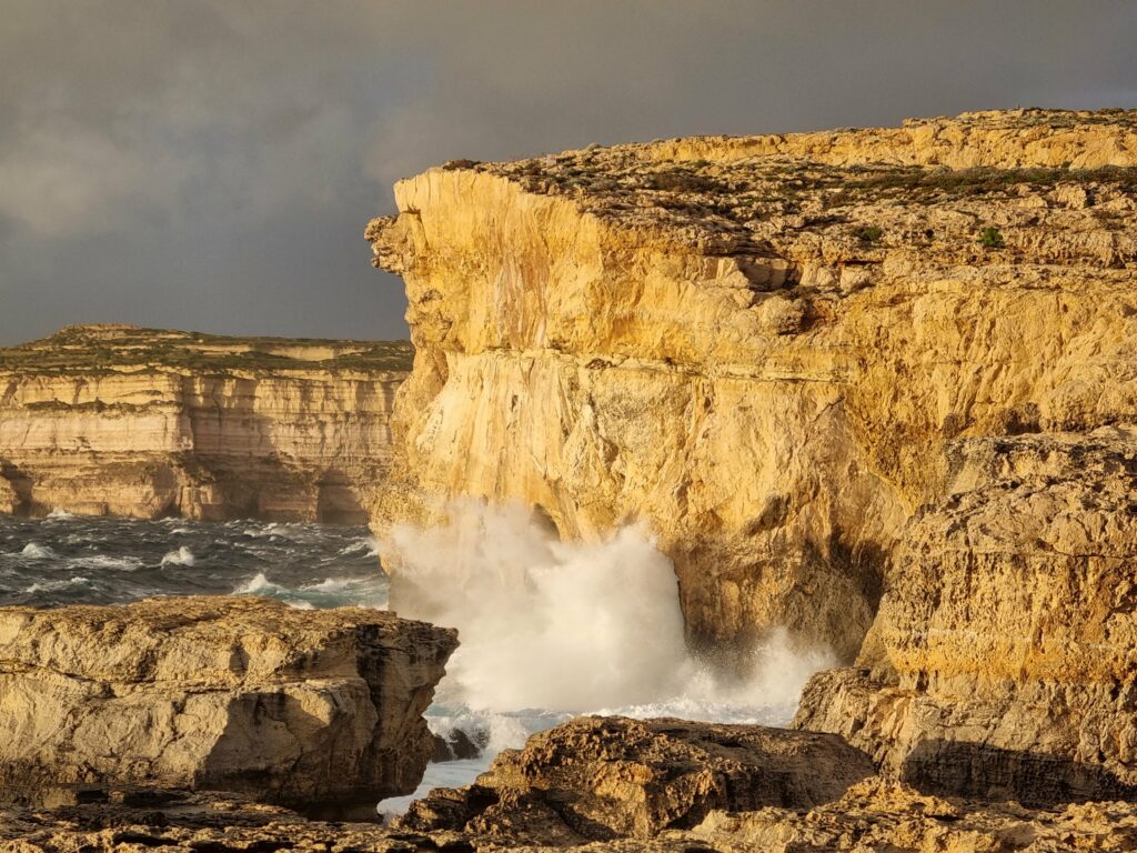 Klify w zatoce Dwejra na Gozo skąpane w promieniach zachodzącego słońca