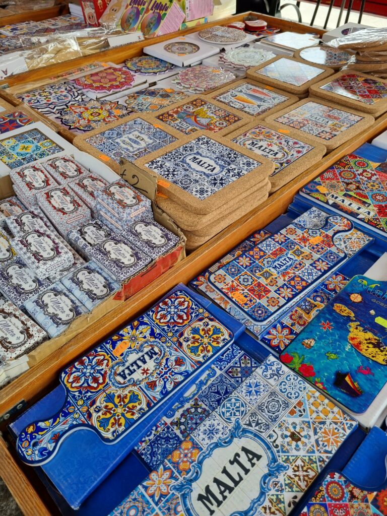 Kolorowe stoiska z pamiątkami, maltańskim miodem i rękodziełem na targu w porcie Marsaxlokk.