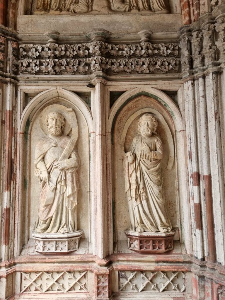 Zabytkowe, kamienne rzeźby postaci świętych w niszach rzeźbionego portalu Zamku Krzyżackiego w Malborku.