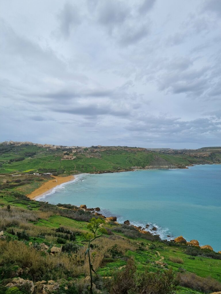 Szeroka plaża Ramla Bay na Gozo otoczona zielonymi wzgórzami