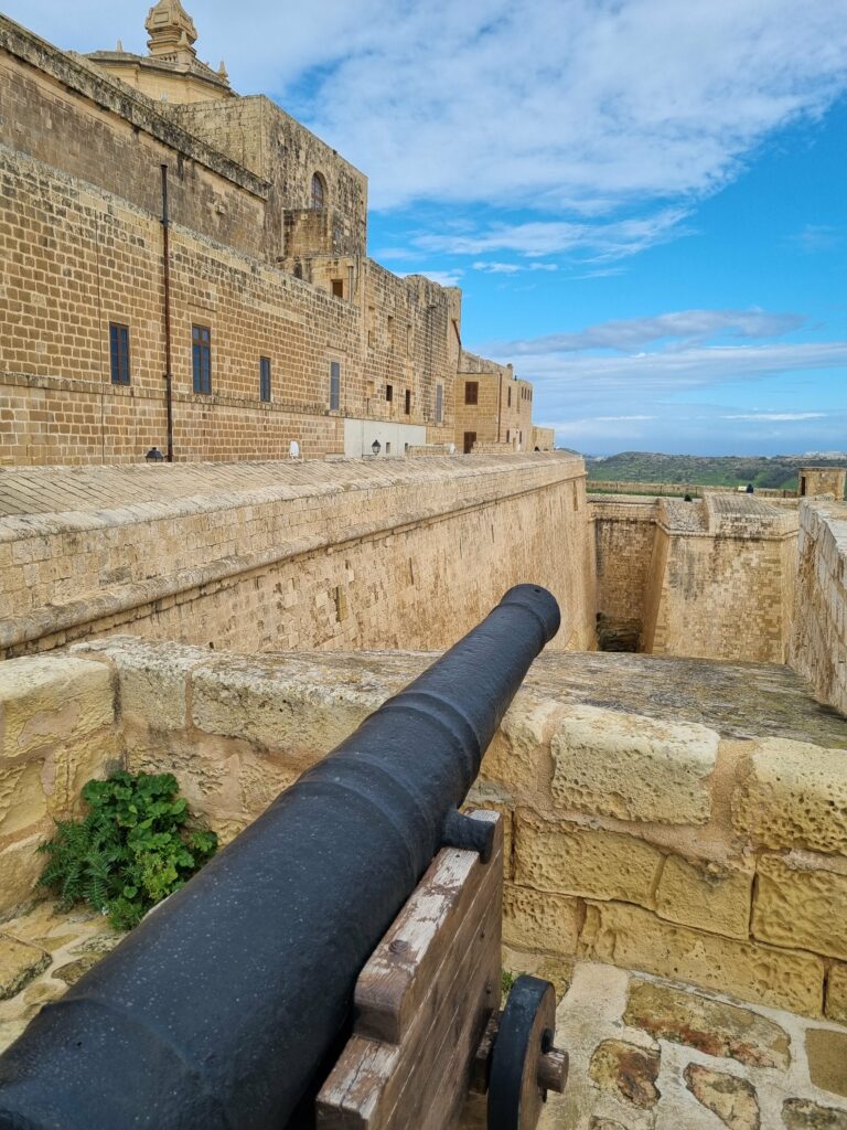 Zabytkowe armaty na murach obronnych Cytadeli w Victorii na Gozo z widokiem na wyspę
