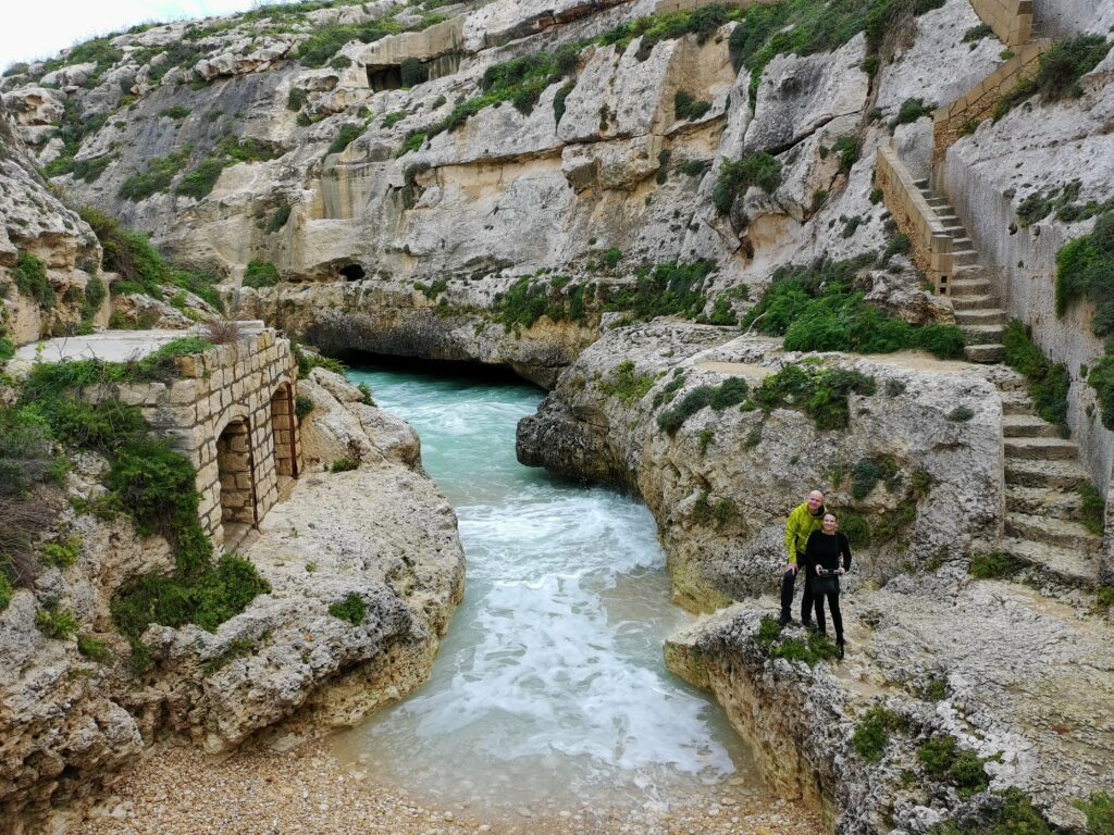 Zejście schodami na małą żwirową plażę w zatoce Wied il-Ghasri na Gozo