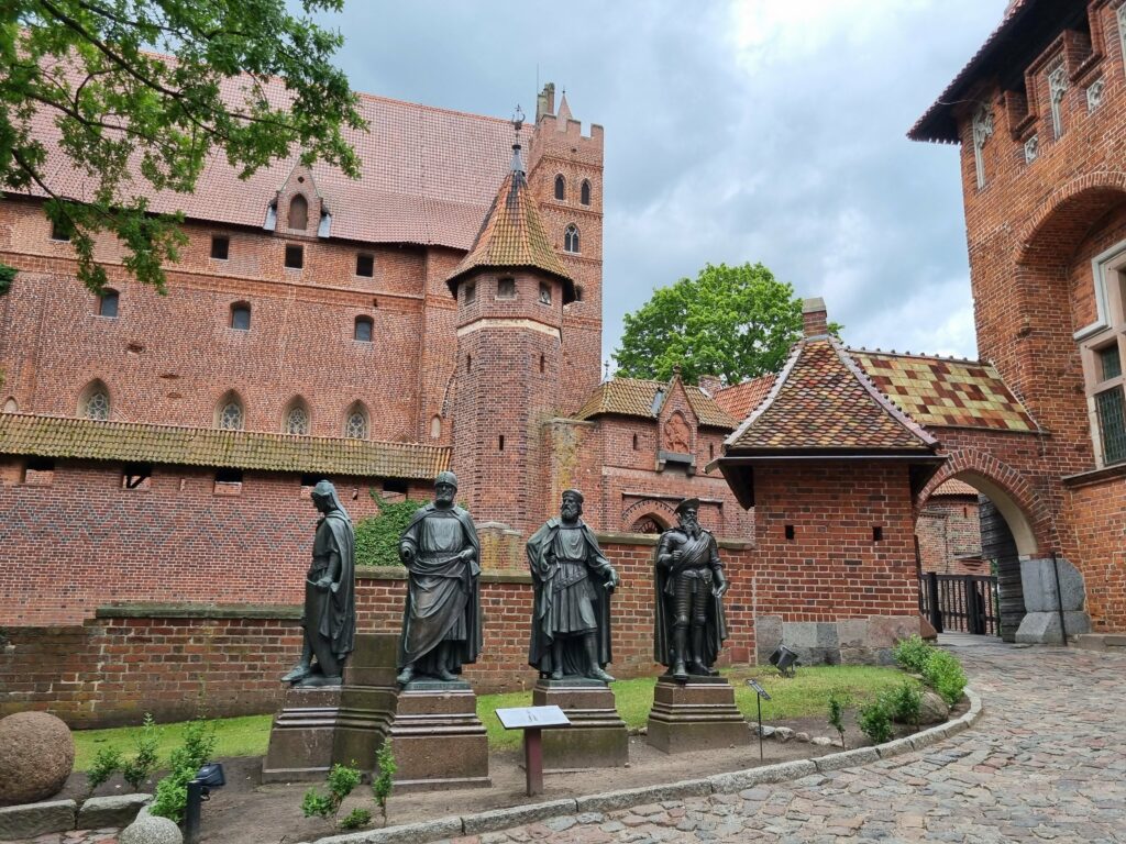 Cztery posągi z brązu przedstawiające wielkich mistrzów zakonu krzyżackiego na dziedzińcu Zamku Średniego w Malborku.