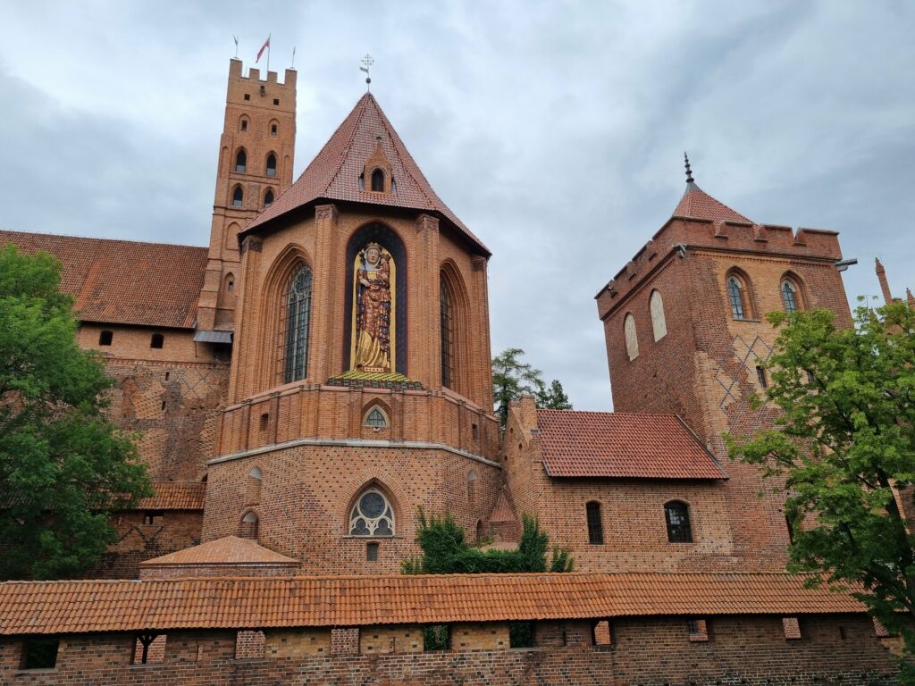 Zamek w Malborku – gotycka ceglana twierdza krzyżacka z widoczną kaplicą i mozaiką Matki Bożej