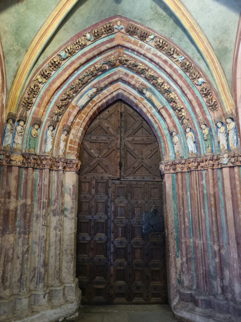 Wielobarwna, gotycka Złota Brama z masywnymi, drewnianymi drzwiami prowadząca do kościoła na Zamku Wysokim w Malborku.