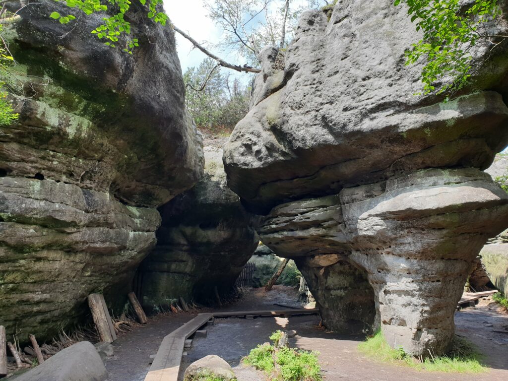 Widok na labirynt Błędne Skały w Górach Stołowych z drewnianymi kładkami między wysokimi skałami.