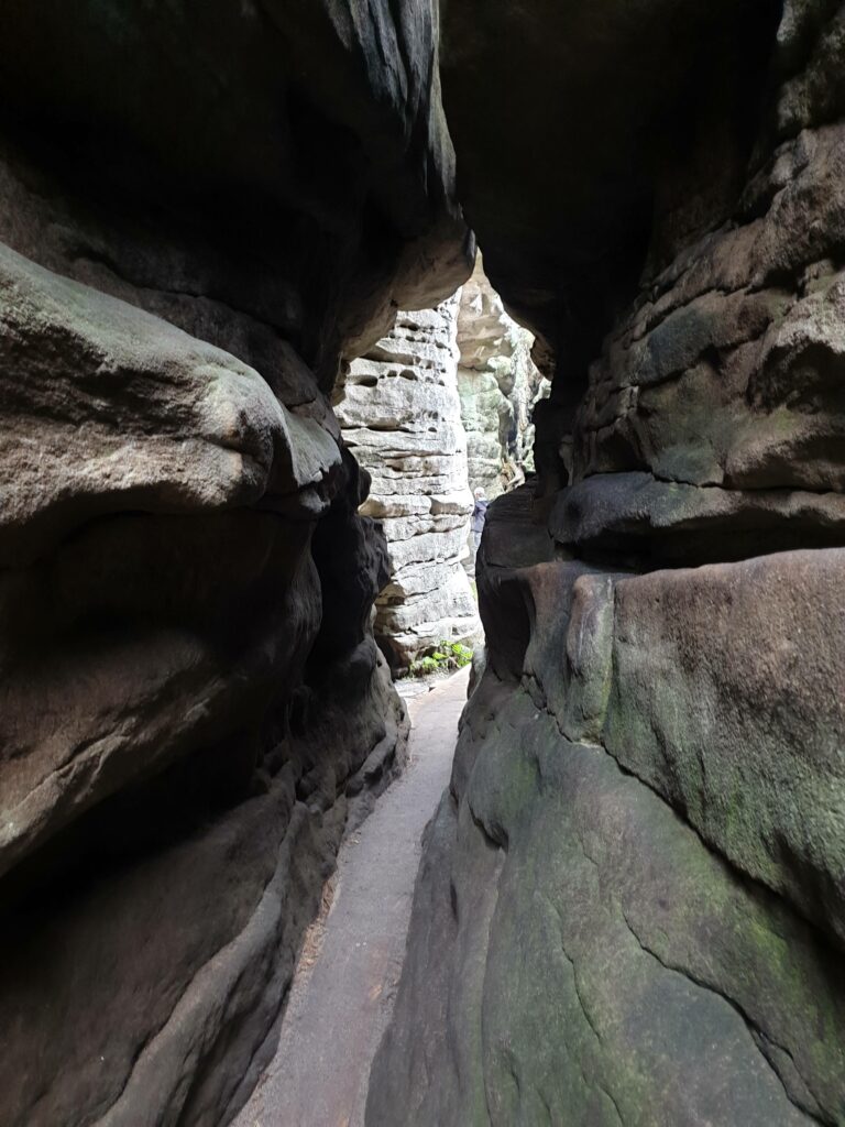 Wąska szczelina skalna w labiryncie Błędne Skały, otoczona potężnymi blokami piaskowca.