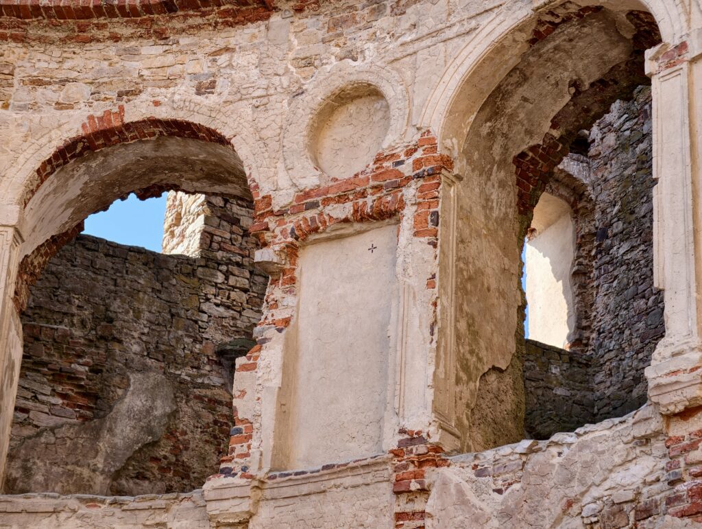 Zbliżenie na kamienne obramowanie okna w ruinach Zamku Krzyżtopór, pokazujące kunszt kamieniarski i stan zachowania piaskowca.
