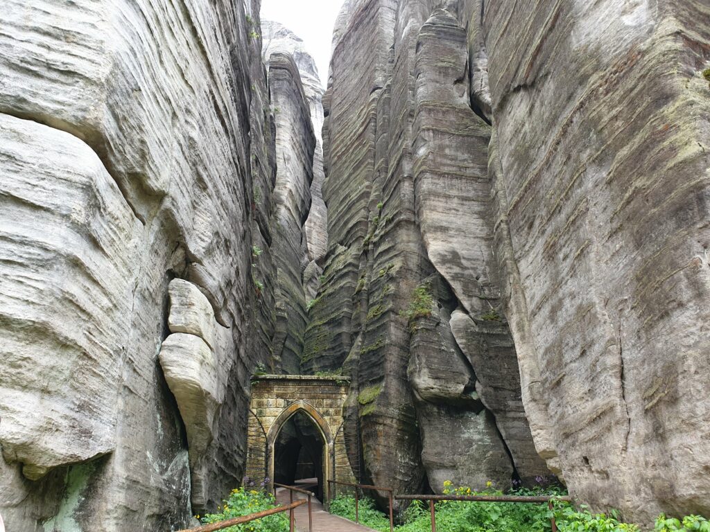 abytkowa, kamienna Gotycka Brama wciśnięta między wysokie, omszałe skały na trasie zwiedzania w rezerwacie w Skalnym Mieście Adršpach