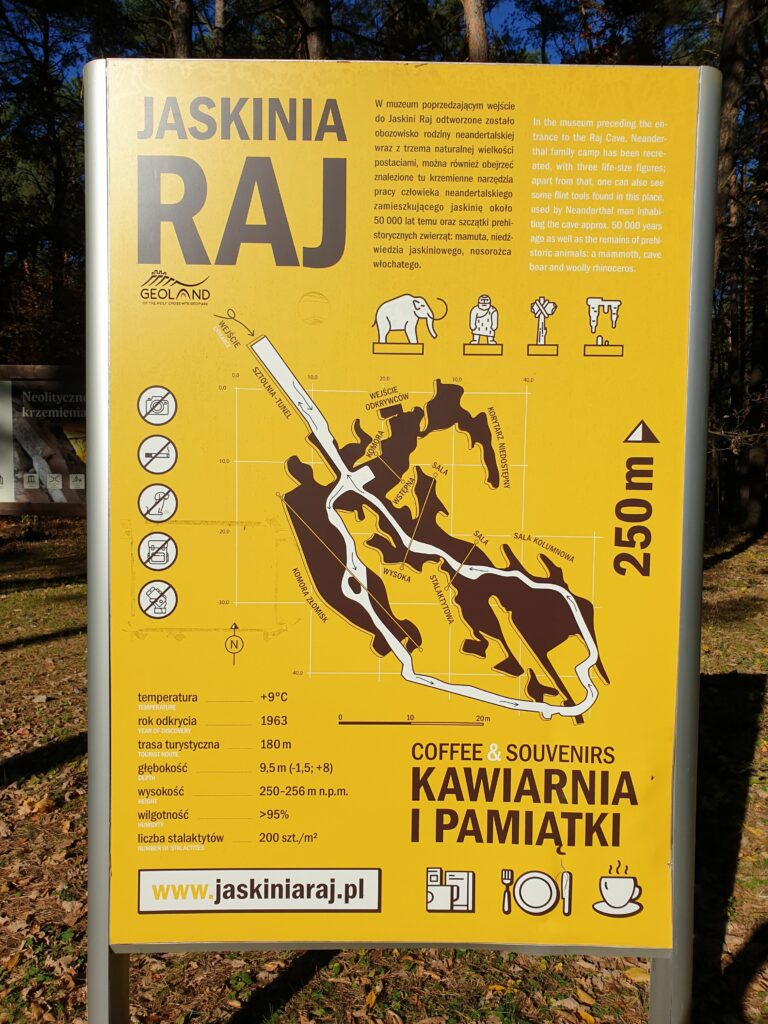 Tablica informacyjna przed wejściem do Jaskini Raj przedstawiająca historię odkrycia jaskini oraz schemat korytarzy podziemnych.