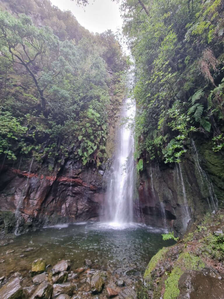 Zbliżenie na krystalicznie czystą wodę spadającą kaskadami do ukrytego w cieniu jeziorka u podnóża wodospadów 25 Źródeł w dolinie Rabaçal.