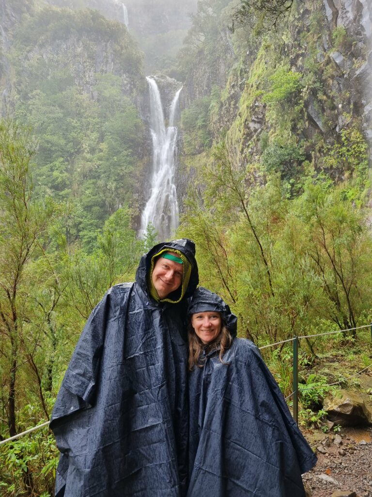 Turyści w kurtkach przeciwdeszczowych na wilgotnym szlaku lewady na Maderze.