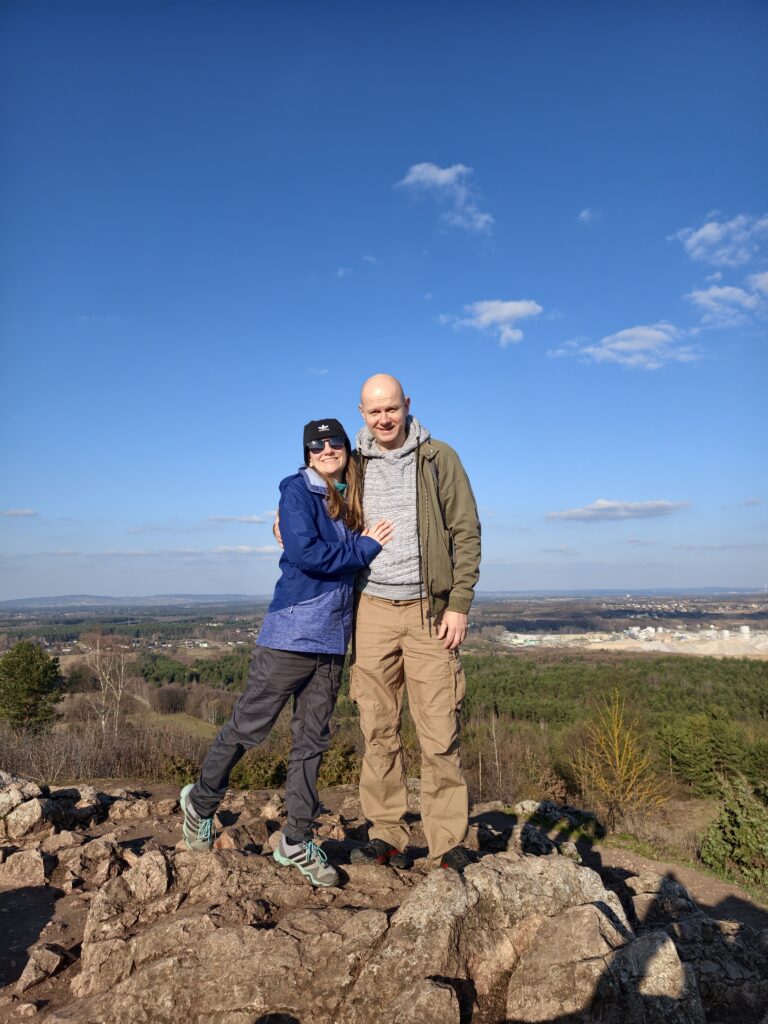 Para turystów stojąca na wapiennych skałach na szczycie góry Miedzianka, podziwiająca rozległą panoramę Gór Świętokrzyskich.