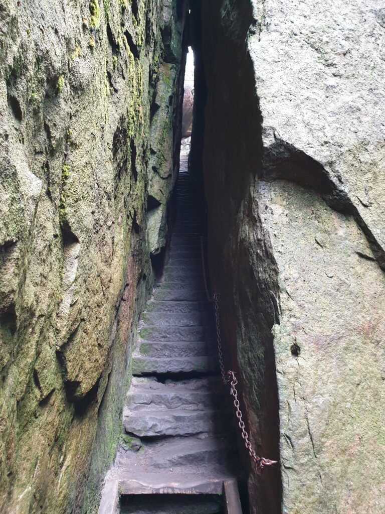 Wąskie przejście i wysokie ściany skalne w szczelinie Piekiełko na Szczelińcu Wielkim.