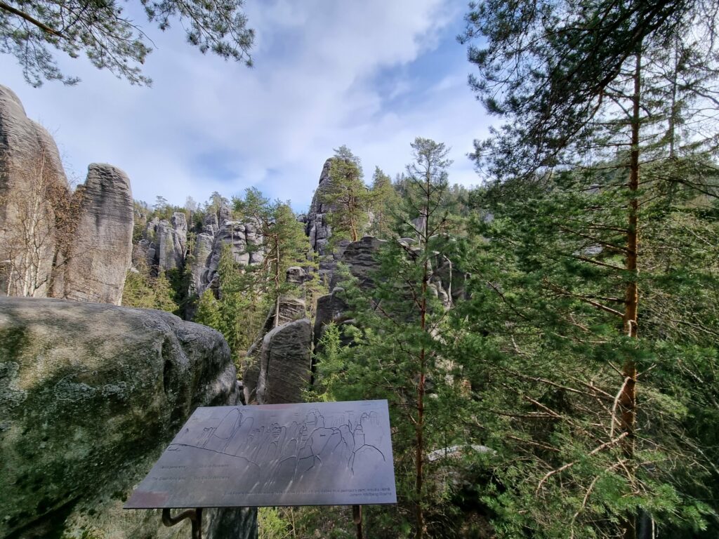 Drewniana platforma widokowa na zielonym szlaku, oferująca rozległą panoramę na potężne formacje z piaskowca w czeskim Skalnym Mieście Adršpach.