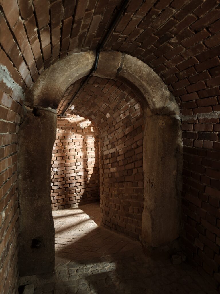 Oświetlone, wąskie korytarze wydrążone w surowej skale lessowej, będące częścią Podziemnej Trasy Turystycznej w Opatowie.