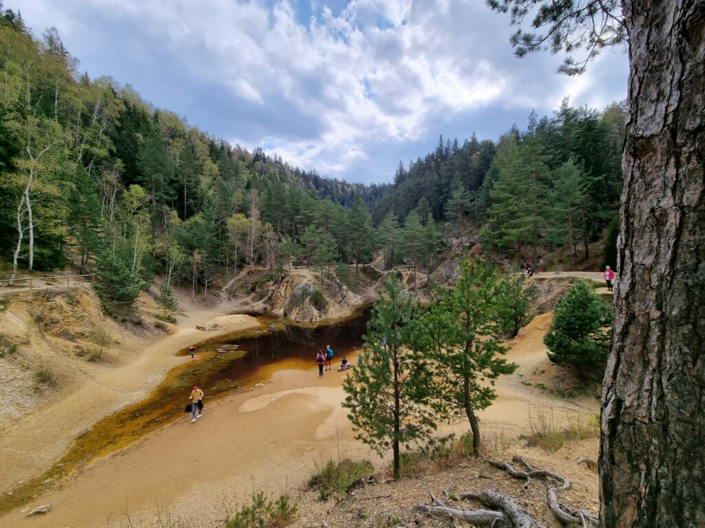 Krwistoczerwona woda Purpurowego Jeziorka i strome, rdzawe zbocza dawnej kopalni w Rudawach Janowickich.