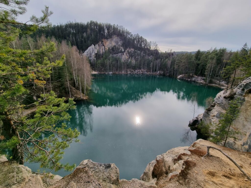 Turkusowe jezioro Pískovna otoczone jasnymi piaskowcami na początku zielonego szlaku w Skalnym Mieście Adršpach.