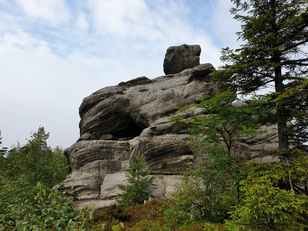 Potężna, warstwowa formacja skalna z piaskowca górująca nad leśną ścieżką w labiryncie na Szczelińcu Wielkim.