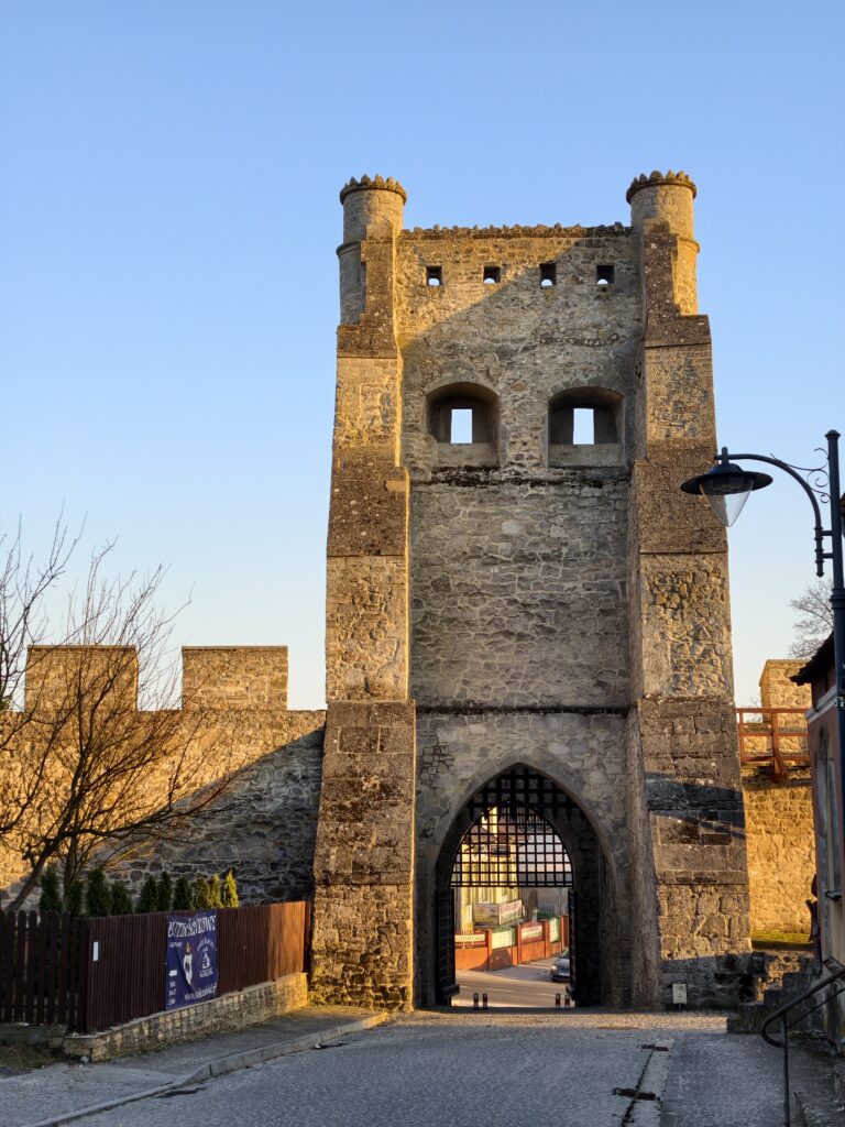 Średniowieczna Brama Krakowska z cegły i kamienia oraz zrekonstruowane mury obronne w Szydłowie.