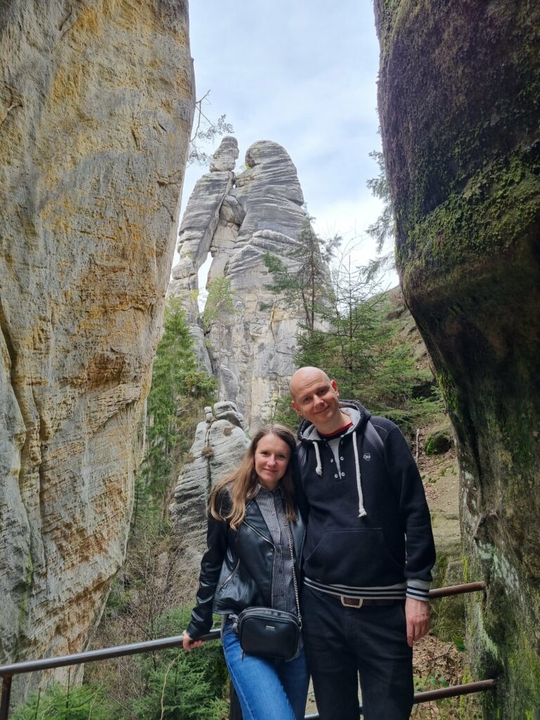 Turyści na zielonym szlaku podziwiający najwyższą, niemal stumetrową formację z piaskowca o nazwie Kochankowie (Milenci) w czeskim Skalnym Mieście Adršpach.