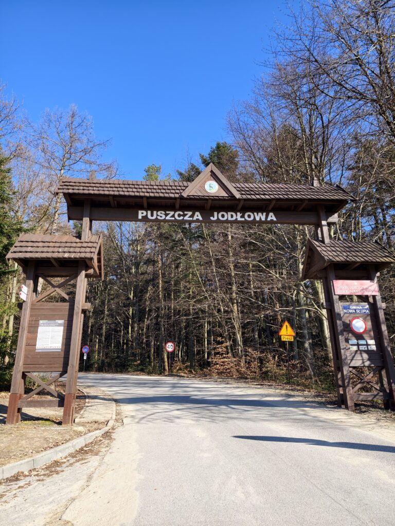 Drewniana brama wejściowa do Świętokrzyskiego Parku Narodowego w Hucie Szklanej, stanowiąca początek czerwonego szlaku.