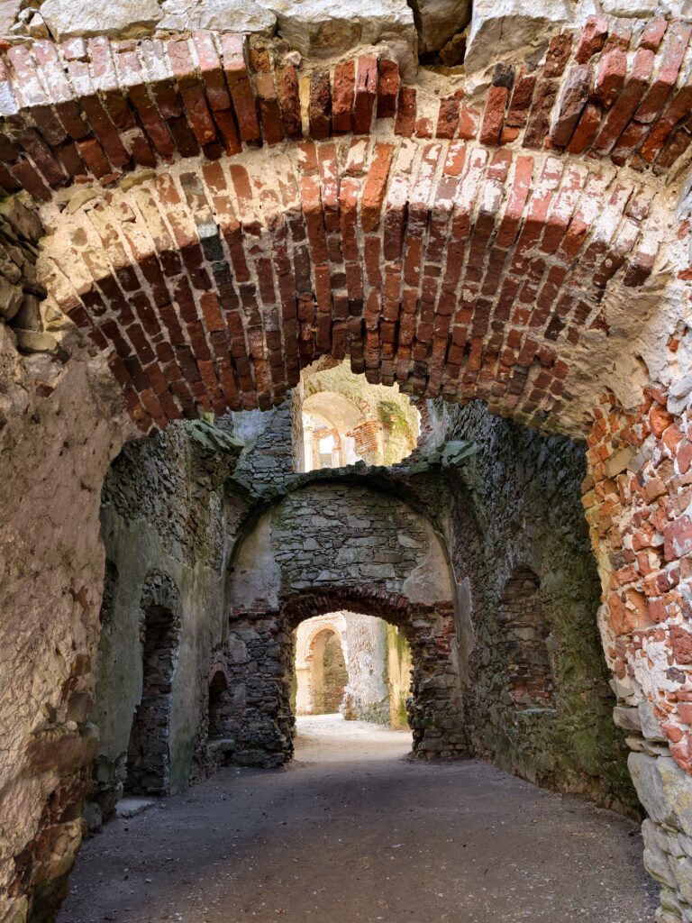 Perspektywa amfilady korytarzy wewnątrz ruin Zamku Krzyżtopór, pokazująca rzędy przejść i grubość murów obronnych.