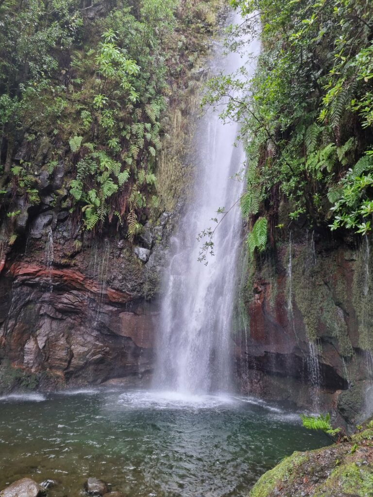 Szmaragdowa laguna i dziesiątki małych wodospadów spływających po porośniętej mchem, półokrągłej ścianie skalnej na końcu szlaku PR6 25 Fontes.