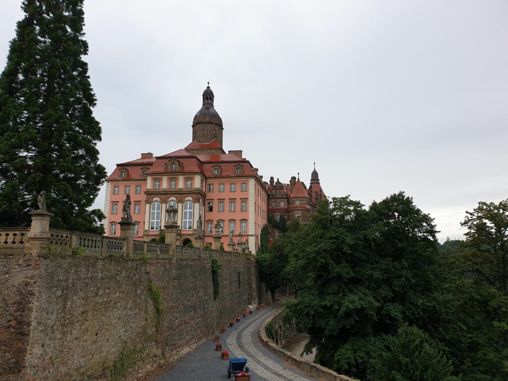 Panoramiczny widok z oddali na monumentalny Zamek Książ w Wałbrzychu. Trzeci co do wielkości zamek w Polsce dumnie wznosi się na skalistym cyplu, otoczony gęstymi lasami Książańskiego Parku Krajobrazowego na Dolnym Śląsku.
