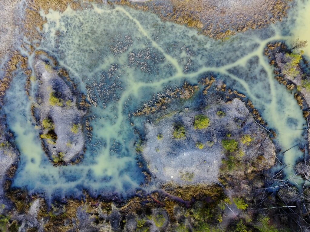 Widok z lotu ptaka na rozległe, zalane wodą wyrobisko dawnej kopalni w rezerwacie Gagaty Sołtykowskie, otoczone gęstym lasem dębowo-sosnowym.