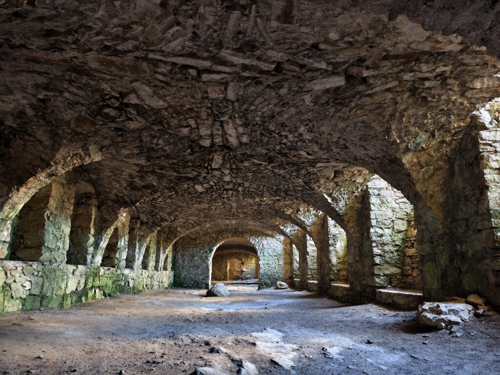 Wnętrze mrocznych, kamiennych korytarzy w podziemiach Zamku Krzyżtopór – trasa turystyczna w Ujeździe.
