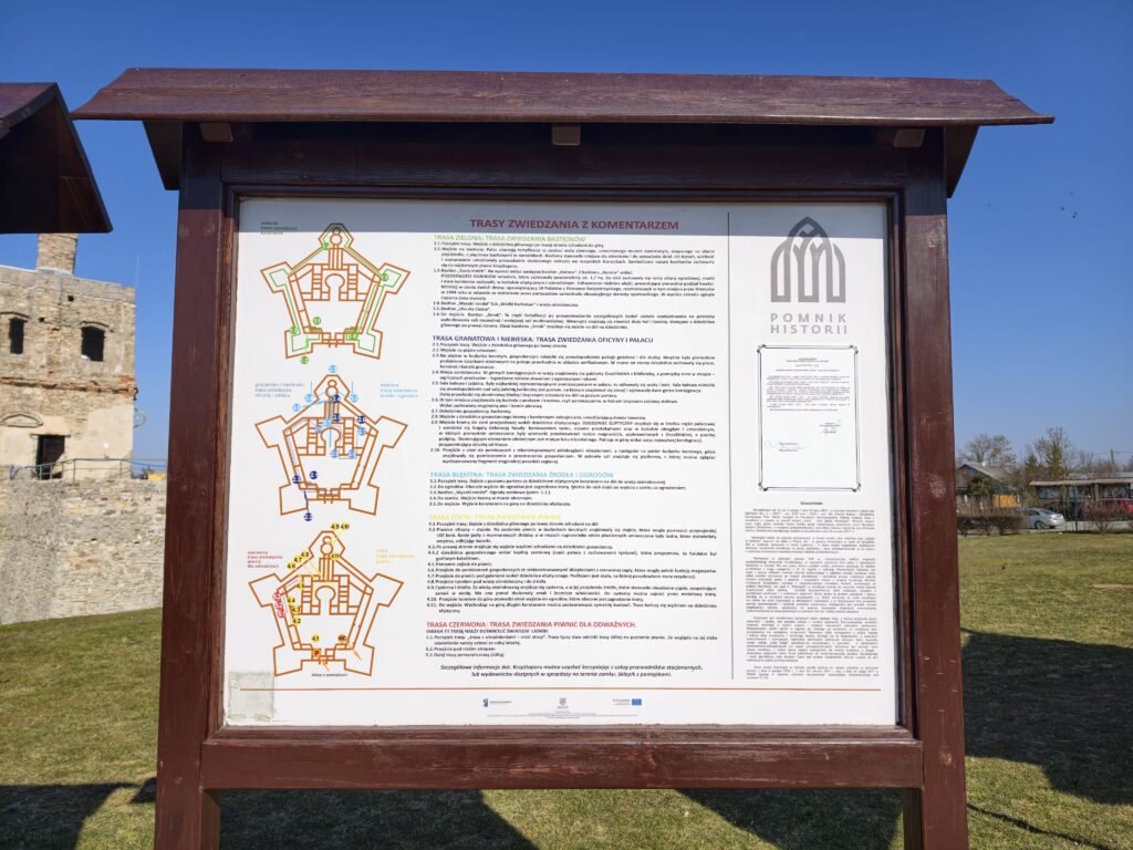 Tablica informacyjna w Zamku Krzyżtopór przedstawiająca mapę i kolorowe trasy zwiedzania: zieloną, żółtą, niebieską i czerwoną.