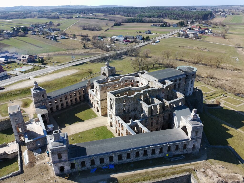 Panoramiczny widok z drona na Zamek Krzyżtopór od strony bocznej, ukazujący bastiony, mury obronne i wewnętrzny dziedziniec.