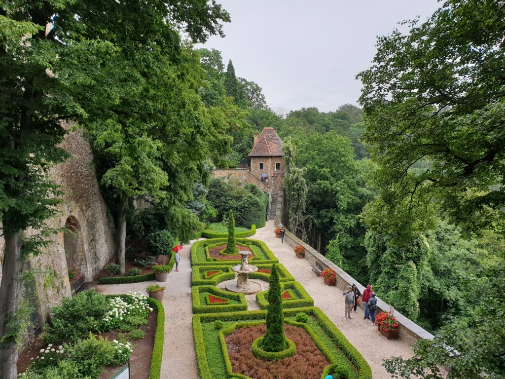 Zabytkowa, kamienna fontanna pośrodku kwitnących rabat kwiatowych na jednym z kaskadowych tarasów ogrodowych Zamku Książ na Dolnym Śląsku.