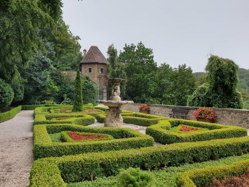 Geometryczne wzory z bukszpanu na kaskadowych tarasach ogrodowych Zamku Książ w Wałbrzychu w sezonie letnim.